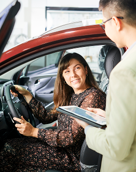 smiling-woman-sitting-car-discussing-some-details-with-insurance-with-salesman-car-salon 1