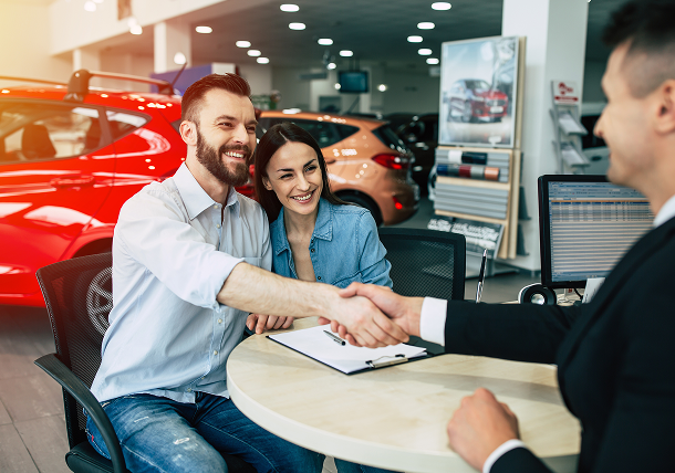 congratulations-your-purchase-seller-car-dealers-gives-keys-new-car-young-happy-woman-with-her-husband 1